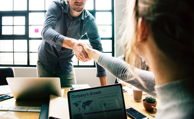 man and woman shaking hands in office setting